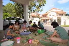 Cháu Nguyễn Như Phú (áo trắng, thứ tư từ trái sang) hoàn thành chiếc bánh chưng tự gói đầu tiên. (Ảnh: Hà Ngọc-Hoàng Nhương/Vietnam+)