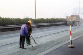 Vệ sinh mặt đường để chuẩn bị thảm nhựa. (Ảnh: Huy Hùng/TTXVN)