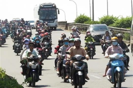 Dòng người đi xe máy đổ về TP.HCM trên Quốc lộ 1A, đoạn qua huyện Bình Chánh. (Ảnh: Hoàng Hải/TTXVN)