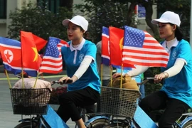 Trong ảnh: Thiếu nữ Việt Nam đạp xe diễu hành với cờ Việt Nam, Mỹ và Triều Tiên trên đường phố Đinh Tiên Hoàng, Hà Nội. (Ảnh: Lâm Khánh/TTXVN)