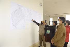 Các hộ dân xem vị trí các ô đất trước khi bốc thăm nhận vị trí đất dịch vụ. (Ảnh: Mạnh Khánh/TTXVN)