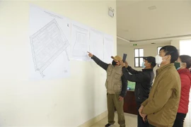Các hộ dân xem vị trí các ô đất trước khi bốc thăm nhận vị trí đất dịch vụ. (Ảnh: Mạnh Khánh/TTXVN)