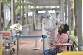 Nhân viên y tế bệnh viện Thanh Nhàn lấy mẫu xét nghiệm COVID-19 cho người đến khám có triệu chứng. (Ảnh: Minh Quyết/TTXVN)