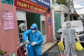 Lực lượng Quân y tại Trạm y tế lưu động số 1 (Phường 6, quận Tân Bình) mang các đồ dùng cần thiết (bình oxy, máy đo nồng độ oxy, ống nghe, nhiệt kế, dung dịch sát khuẩn, khẩu trang…) để đến nhà F0. (Ảnh: Mạnh Linh/TTXVN)