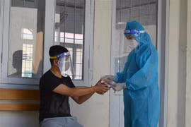 Cán bộ Trạm Y tế xã Bình Thành, huyện Thanh Bình, tỉnh Đồng Tháp đến kiểm tra sức khỏe và hướng dẫn sử dụng thuốc hỗ trợ điều trị COVID-19 cho đối tượng F0 đang điều trị tại nhà. (Ảnh: Nhựt An/TTXVN)