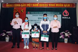 Lãnh đạo Ngân hàng Chính sách xã hội Chi nhánh tỉnh Sơn La ủn)g hộ máy tính cho các học sinh gia đình nghèo, có hoàn cảnh khó khăn. (Ảnh: Quang Quyết/TTXVN