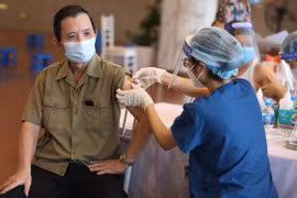 Nhân viên y tế vaccine phòng COVID-19 cho người dân tại điểm tiêm chủng quận Hoàn Kiếm (Hà Nội). (Ảnh: Minh Quyết/TTXVN)