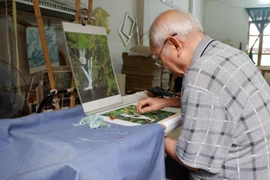 Đã bước sang tuổi “xưa nay hiếm,” ông Nguyễn Quốc Sự vẫn không rời khung thêu. (Ảnh: Thu Minh/Vietnam+)