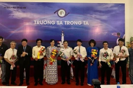 Tặng hoa cho các nhà báo, nghệ sỹ nhiếp ảnh có ảnh tham gia triển lãm. (Ảnh: PV/Vietnam+)