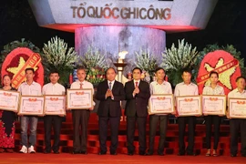 Thủ tướng Nguyễn Xuân Phúc trao bằng Tổ quốc ghi công cho thân nhân các gia đình liệt sỹ. (Ảnh: Thống Nhất/TTXVN)