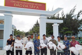Cán bộ, chiến sỹ đảo Đá Tây đang hỗ trợ gạo cho bà con ngư dân tỉnh Ninh Thuận. (Ảnh: TTXVN phát)