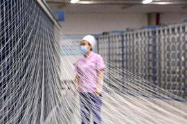 Công nhân làm việc tại một nhà máy dệt ở thành phố Thạch Gia Trang, tỉnh Hà Bắc, Trung Quốc. (Ảnh: THX/TTXVN)