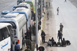 Xe buýt chở các tay súng nổi dậy cùng gia đình rời khỏi thành phố Harasta, ngoại ô Đông Ghouta ngày 22/3. (Nguồn: THX/TTXVN)