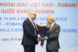 Chủ tịch Hội Hữu nghị Việt Nam-Romania Tống Văn Nga tặng hoa, chúc mừng 102 năm Quốc khánh Romania. (Ảnh: Văn Điệp - TTXVN)