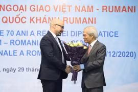 Chủ tịch Hội Hữu nghị Việt Nam-Romania Tống Văn Nga tặng hoa, chúc mừng 102 năm Quốc khánh Romania. (Ảnh: Văn Điệp - TTXVN)