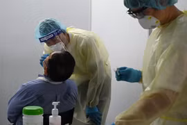 Nhân viên y tế lấy mẫu dịch xét nghiệm COVID-19 cho người dân tại Singapore. (Ảnh: AFP/TTXVN)