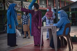 Kiểm tra thân nhiệt phòng lây nhiễm COVID-19 tại một trường học ở Kuala Lumpur, Malaysia. (Ảnh: AFP/TTXVN)