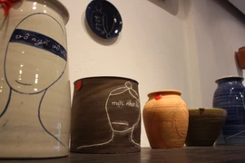 Những câu kinh Phật trên gốm, tranh của họa sỹ Lê Thiết Cương đều chỉ ngắn gọn, cô đọng, súc tích trong 4 tới 5 chữ, người xem tùy ý cảm nhận, diễn giải tác phẩm theo trải nghiệm của cá nhân mình. (Ảnh: Minh Anh/Vietnam+)