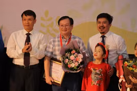 Ủy viên Ban Chấp hành Trung ương Đảng, Tổng Giám đốc TTXVN Nguyễn Đức Lợi (trái) và ông Lê Xuân Thành, Tổng biên tập Báo Thể thao và Văn hóa trao giải "Hiệp sĩ Dế Mèn" cho nhà văn Nguyễn Nhật Ánh. (Ảnh: Minh Anh/Vietnam+)