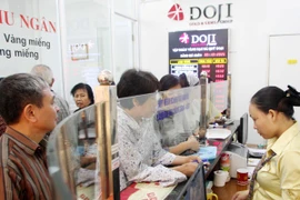 Khách hàng đang giao dịch vàng miếng tại hệ thống DOJI (Ảnh: TTXVN)