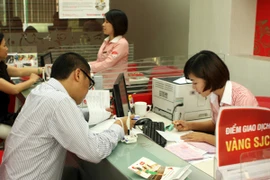 Khách hàng đang giao dịch vàng miếng tại hệ thống SJC (Ảnh: TTXVN)