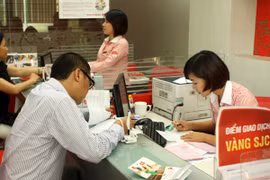 Khách hàng đang giao dịch vàng miếng tại hệ thống SJC (Ảnh: TTXVN)