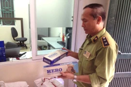 Cán bộ Đội Quản lý thị trường số 5 đang kiểm tra số thuốc lá ngoại nhập lậu bị tịch thu trên xe khách 74B-00.075 (Ảnh: Đức Duy/Vietnam+)