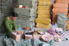 Lực lượng chức năng đang kiểm tra số hàng hóa gồm: ô mai và hoa quả khô, thu giữ được tại khu vực chợ Ninh Hiệp (Ảnh: Đức Duy/Vietnam+)