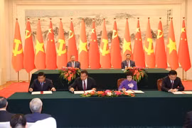 Lễ ký Thỏa thuận hợp tác nghiệp vụ giữa Thông tấn xã Việt Nam với Tân Hoa xã (bên phải) và hợp tác về đầu tư (bên trái) giữa hai nước. (Ảnh: Trí Dũng/TTXVN)
