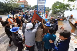  Các ngư dân chuyển thuyền đi biển xuống vùng lũ tại huyện Lệ Thủy hỗ trợ công tác cứu trợ đồng bào. (Ảnh: Thành Đạt/TTXVN)
