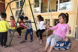 Các cháu chơi trò chơi xích đu làm từ lốp xe hỏng. (Ảnh: Tiến Vĩnh/TTXVN)