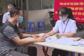 Trao tiền hỗ trợ cho các đối tượng gặp khó khăn do dịch bệnh COVID-19 theo tinh thần Nghị quyết 42 của Chính phủ. (Ảnh minh họa. Nguồn: TTXVN)