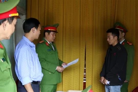 Cơ quan chức năng đọc quyết định khởi tố vụ án, khởi tố bị can và lệnh tạm giam 2 tháng đối với Ngô Xuân Sĩ (áo đen) về hành vi lạm dụng tín nhiệm, chiếm đoạt tài sản, là hàng hóa cứu trợ người dân vùng lũ lụt. (Ảnh: Văn Tý/TTXVN)