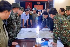 Chủ tịch UBND huyện Phong Điền Nguyễn Văn Bình (sơ mi ngắn tay xanh nhạt) họp bàn trước lúc lên đường cứu trợ đoàn công nhân mất tích tại Thủy điện Rào Trăng 3. (Ảnh: TTXVN phát)