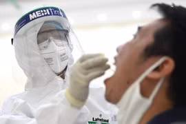 Nhân viên y tế tiến hành lấy mẫu dịch hầu họng để xét nghiệm bằng phương pháp RT-PCR. (Ảnh: Thành Đạt/TTXVN)