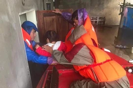 Anh Đặng Hồng Quân, Chỉ huy trưởng quân sự xã Tân Lâm Hương (huyện Thạch Hà, Hà Tĩnh) miệt mài sơ tán người dân trong nước lũ. (Ảnh: TTXVN phát)