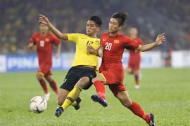 Phan Văn Đức (20) tranh bóng với hậu vệ Malaysia. (Ảnh: Hoàng Linh/TTXVN)