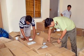 Lực lượng chức năng kiểm tra số lượng hàng hoá bị thu giữ. (Ảnh: Huỳnh Thế Anh/TTXVN)