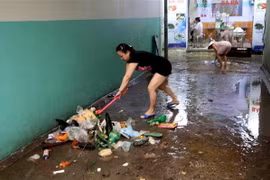 Người dân phường Vĩnh Trung (Đà Nẵng) thu gom rác thải tràn ra đường để tránh tắc nghẽn hệ thống thoát nước trên đường. (Ảnh: Trần Lê Lâm/TTXVN)