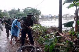 Cán bộ, chiến sỹ Bộ đội Biên phòng tỉnh Quảng Nam giúp đỡ người dân xã Tam An, huyện Phú Ninh, dọn dẹp vệ sinh môi trường sau mưa lụt. (Ảnh: Đỗ Trưởng/TTXVN)