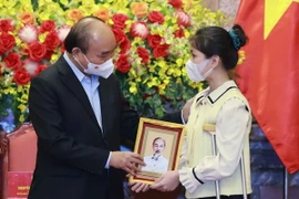 Chủ tịch nước Nguyễn Xuân Phúc tặng chân dung Chủ tịch Hồ Chí Minh cho học sinh xuất sắc trong cuộc thi “Vì một Việt Nam tất thắng.” (Ảnh: Thống Nhất/TTXVN)