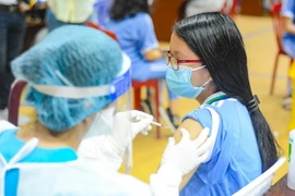 Học sinh thực hiện việc tiêm chủng. (Ảnh: Văn Dũng/TTXVN)