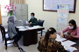 Người lao động đang được hướng dẫn làm thủ tục nhận hỗ trợ qua ứng dụng trực tuyến bảo hiểm xã hội số VssID. (Ảnh: Đại Nghĩa/TTXVN)