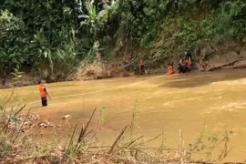 Lực lượng chức năng tổ chức tìm kiếm thi thể nạn nhân bị nước cuốn trôi. (Ảnh: TTXVN phát)