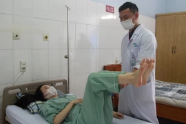 Bác sỹ Bệnh viện Bãi Cháy kiểm tra cử động của bệnh nhân Nguyễn Minh Nguyệt sau khi phẫu nắn vẹo cột sống thành công. (Ảnh: TTXVN phát)