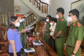 Đại diện Cơ quan Cảnh sát điều tra đọc lệnh khởi tố, bắt tạm giam ông Đoàn Thế Nam (áo trắng, giữa, bên phải), nguyên Hiệu trưởng Trường Cao đẳng Nghề Bình Phước. (Ảnh: TTXVN phát)