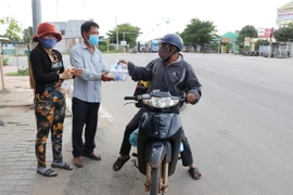 Tặng các suất cơm, nước uống miễn phí cho những người trở về quê bằng xe máy từ các tỉnh, thành phía Nam trên Quốc lộ 1A đoạn qua thành phố Phan Rang-Tháp Chàm, tỉnh Ninh Thuận. (Ảnh: Nguyễn Thành/TTXVN)