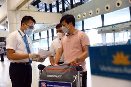 Nhân viên của Vietnam Airlines kiểm tra giấy tờ của hành khách trước khi vào làm thủ tục. (Ảnh: Huy Hùng/TTXVN)
