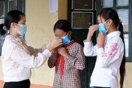 Giáo viên trường Tiểu học và Trung học cơ sở A Lù huyện Bát Xát hướng dẫn học sinh cách đeo khẩu trang đúng cách. (Ảnh: Quốc Khánh/TTXVN)