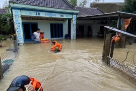 Người dân huyện Tuy Phước được lực lượng chức năng hỗ trợ di dời. (Ảnh: Tường Quân/TTXVN)